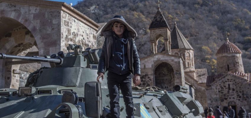 A boy stands on a tank in Dadivank monastery